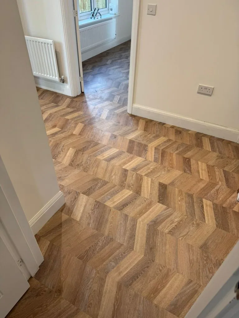 Chevron Karndean Knight Tile warm oak flooring running through a hallway into a rear room